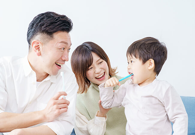 両親と子どもが歯を磨く様子